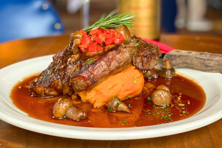 A steak dish with sweet potatos and a jus