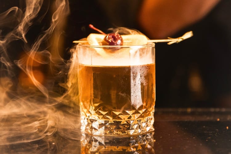 A cocktail on a bar with smoke around it