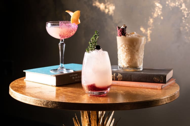 Three cocktails on top of vintage books on a table