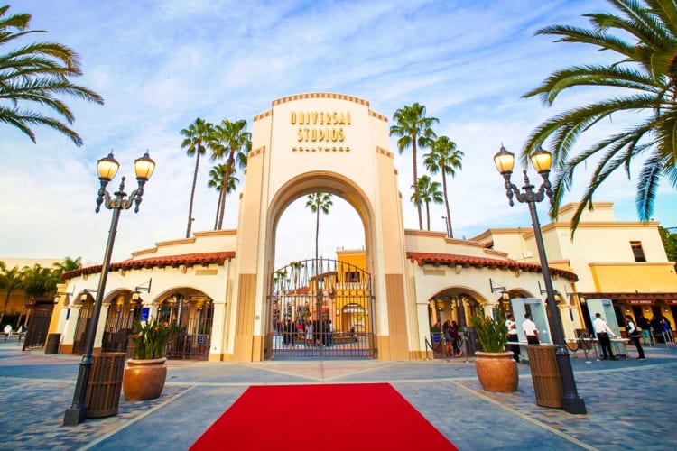 An arch that says Universal Studios next to a red carpet and palm trees