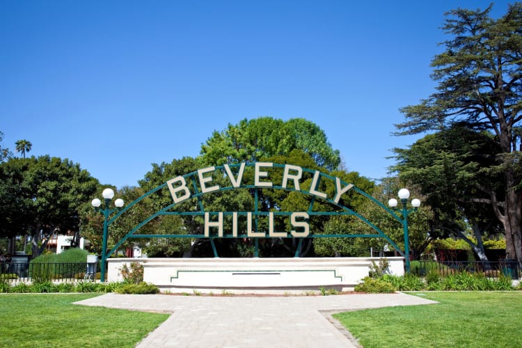 A Beverly Hills sign next to trees and grass with a path through it