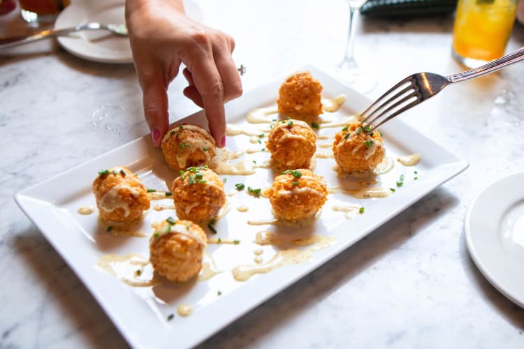 People taking arancini off of a plate