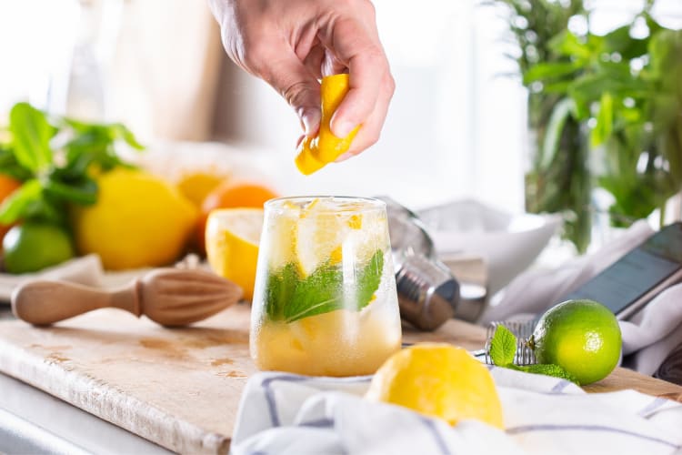 A person squeezing lemon into a homemade cocktail