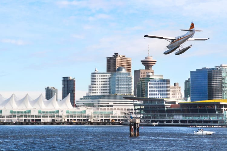 A seaplane flying over water near a city skyline