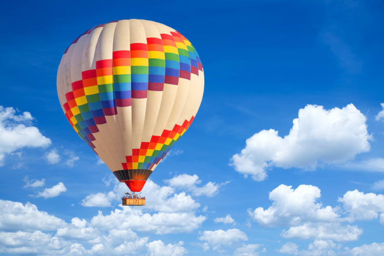 A colorful hot air balloon in the blue sky with white clouds