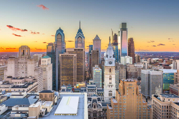 A city skyline with tall buildings at sunset
