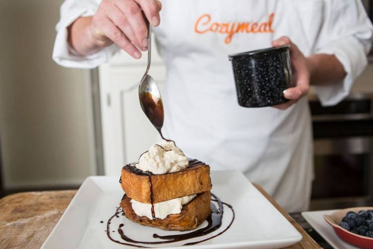 A chef pouring chocolate sauce onto French toast