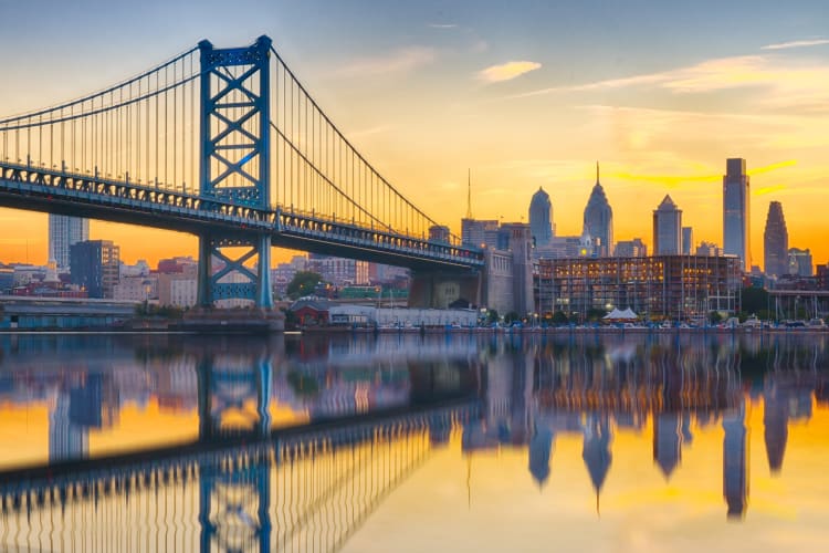 A river with a bridge across it next to a city skyline