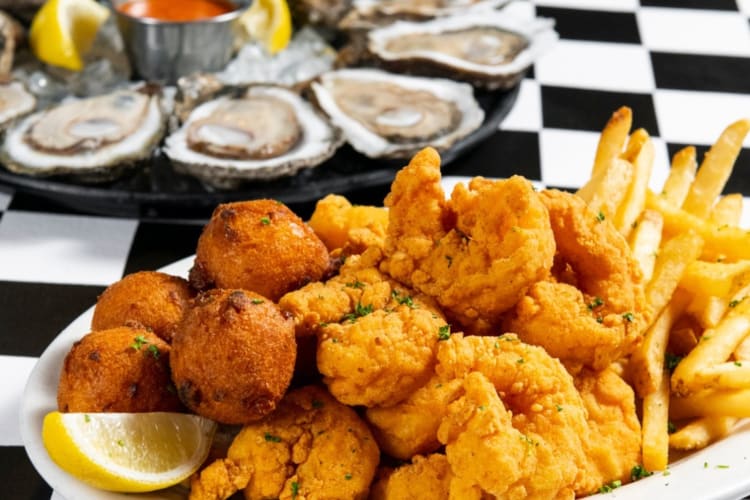 Fries and fried shimp next to oysters on a checkered table