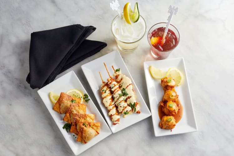 Bar snacks and cocktails next to navy blue napkins