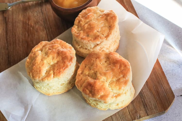 Three biscuits on parchment paper, on top of a wooden surface