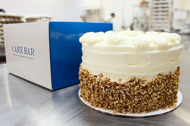 A cake on a counter next to a box that says Cake Bar