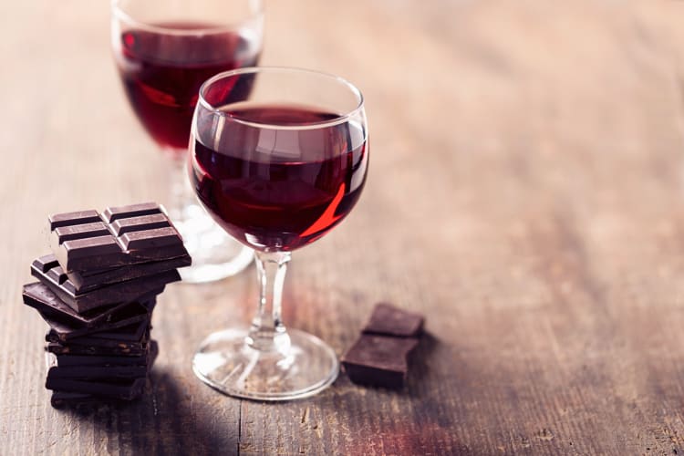 Two glasses of red wine with blocks of chocolate