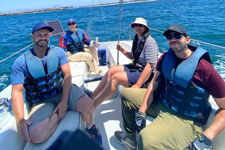 Four people wearing life jackets while on a sail boat