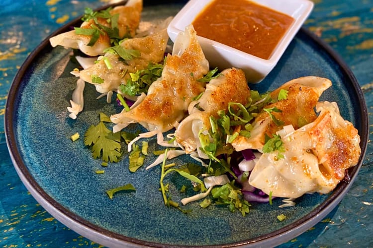 Chicken momo dumplings with a side sauce from Bombay Street Kitchen