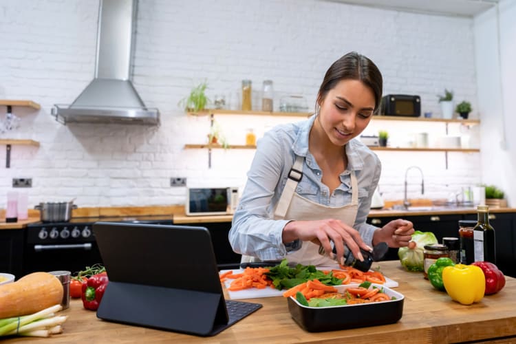 A woman spicing vegetables while taking an online cooking class