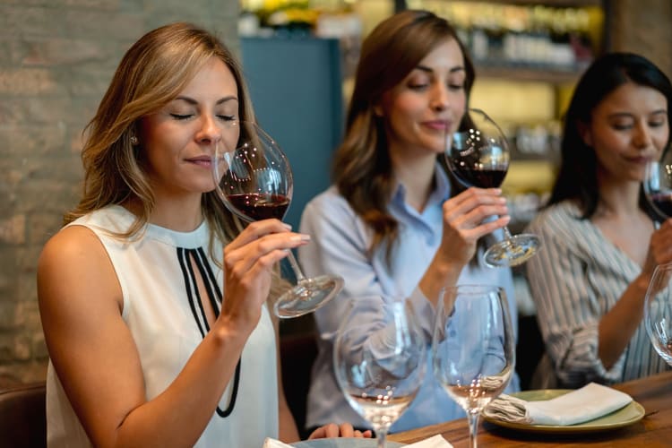 Three ladies taking in the scent of wine while doing a wine tasting