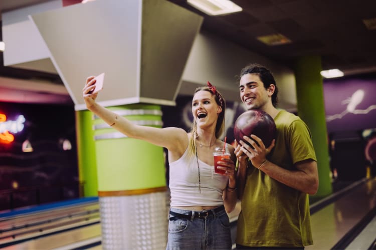 A couple taking a selfie while on a date at a bowling alley