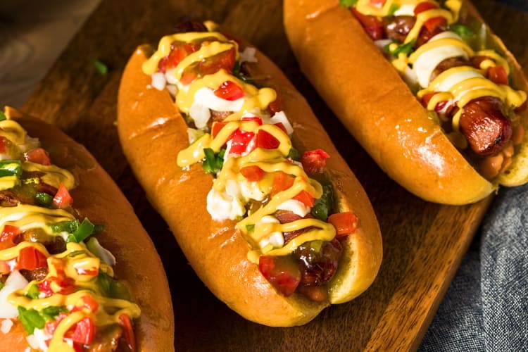 Three hot dogs with a variety of toppings and sauces as an example of fast food in Atlanta