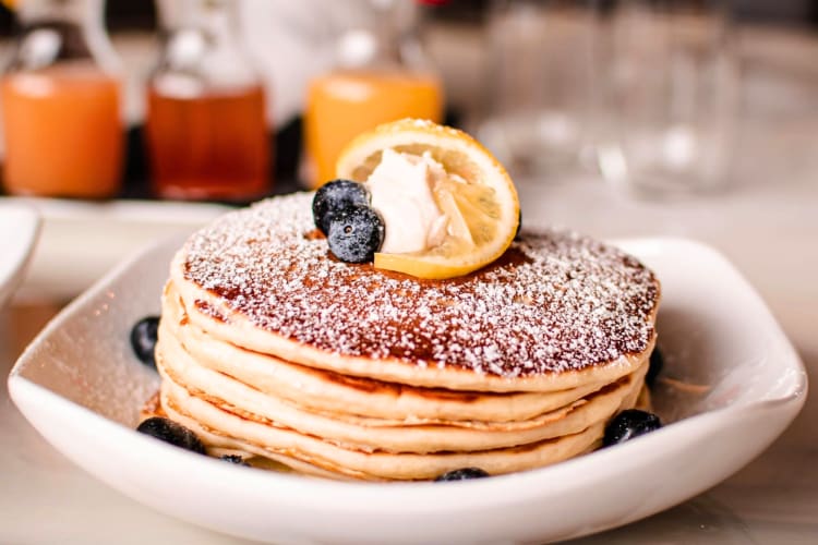 A stack of pancakes with blueberries and lemon