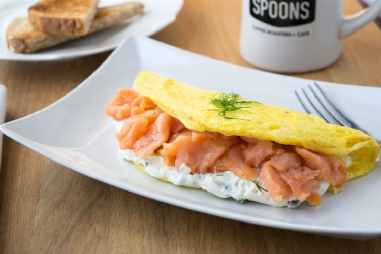 A salmon omelette on a plate next to a coffee mug