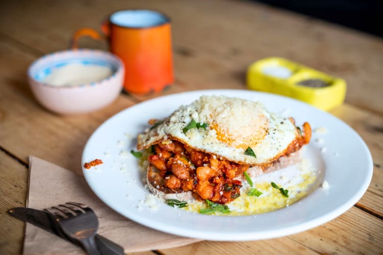 A plate of toast with beans in tomato sauce and fried egg