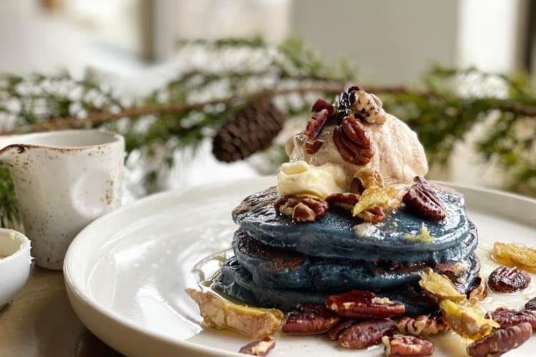 A plate of purple yam pancakes with coconut cream and pecans