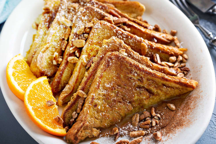 French toast on a plate with pecans and lemon slices