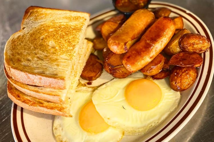 A breakfast dish with toast, sausages and eggs on a counter