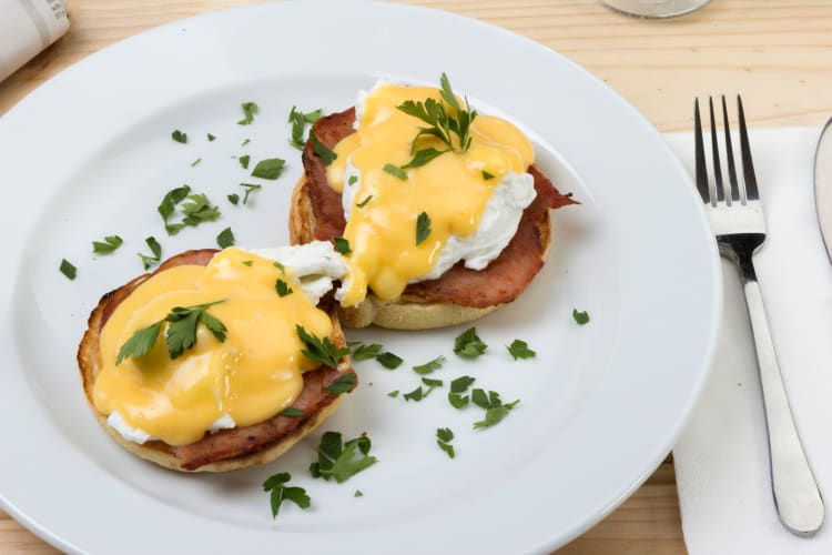 Eggs Benedict sprinkled with parsley.