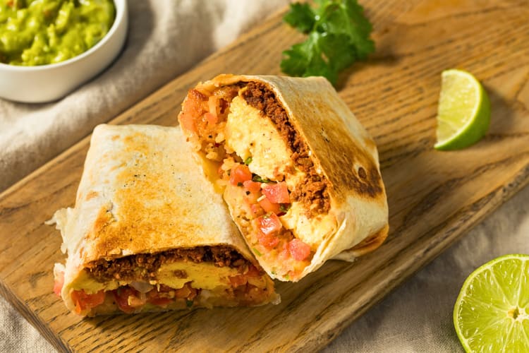 Breakfast burrito cut in half and served on a wooden board