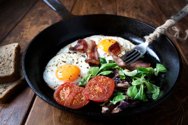 Tomatoes, eggs, bacon, and salad in a cast iron pan