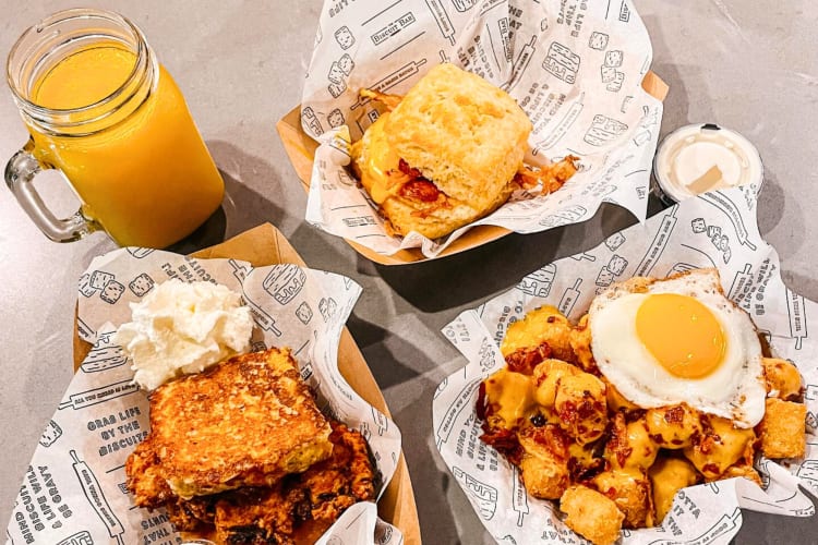 Breakfast dishes in cardboard take-out containers and a glass with orange juice