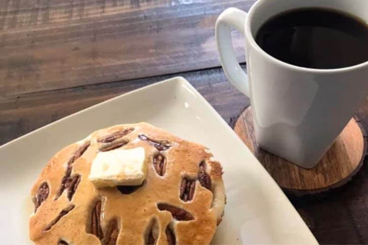 Pecan pancakes on a plate next to a cup of coffee