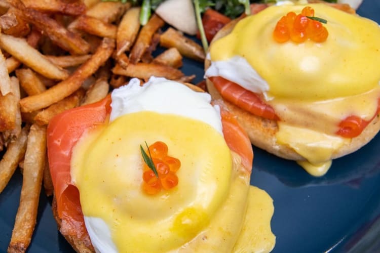 Salmon eggs Benedict next to fries