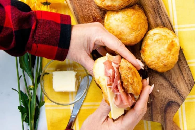 A person holding a biscuit sandwich