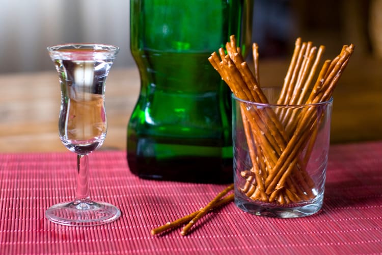 A tulip-shaped glass of liquor next to pretzel sticks