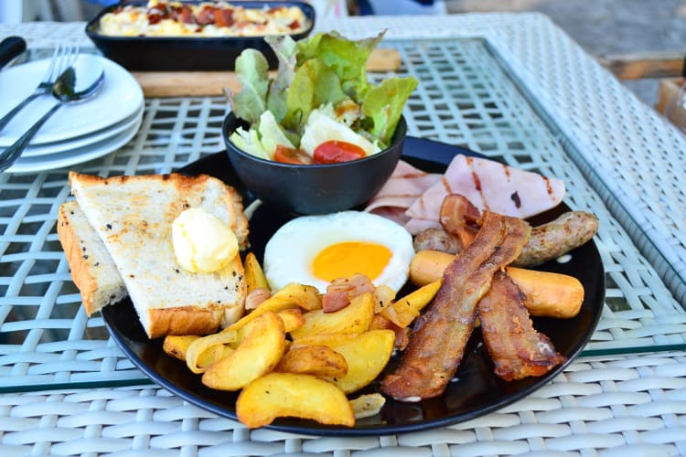 Breakfast with an egg, bacon, sausage, ham, potato wedges, salad and toast