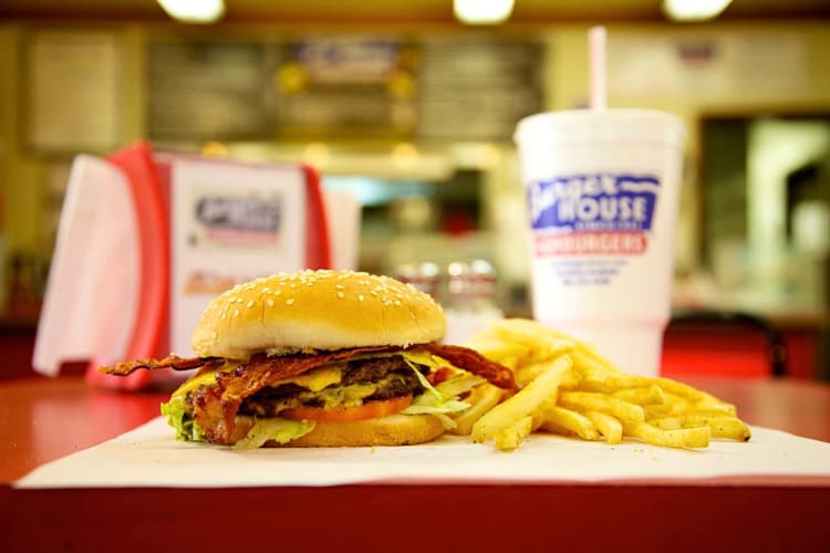 Side view of a burger and fries with a cup in the background, from Burger House