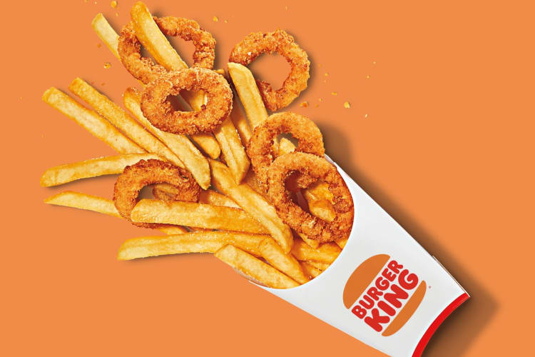 Fries and onion rings on an orange background