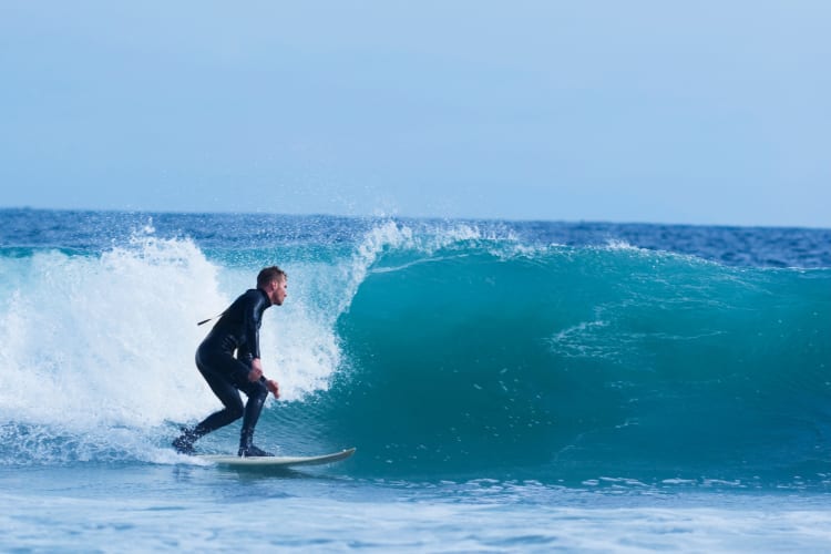 A person surfing in the ocean under a blue sky