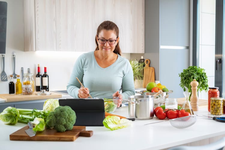 A woman in her kitchen cooking with a tablet in front of her