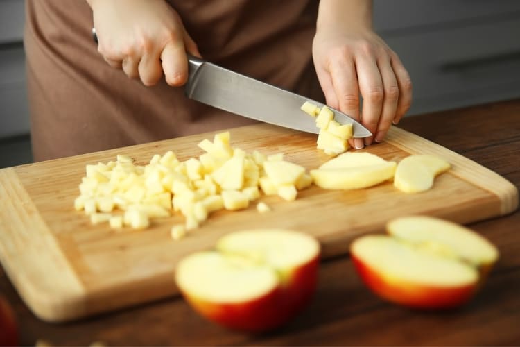 A person chopping apples on a board