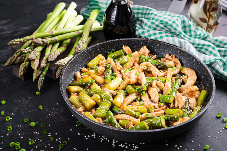 An aspragus and chicken stir fry in a pan