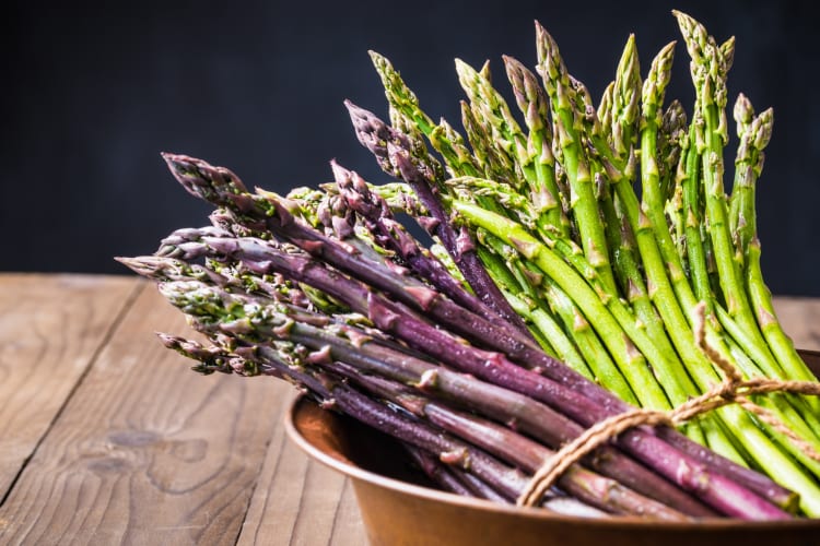 Green and purple asparagus in a bowl