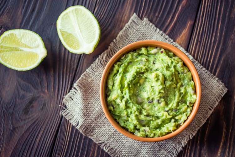 Mashed avocado next to halved limes