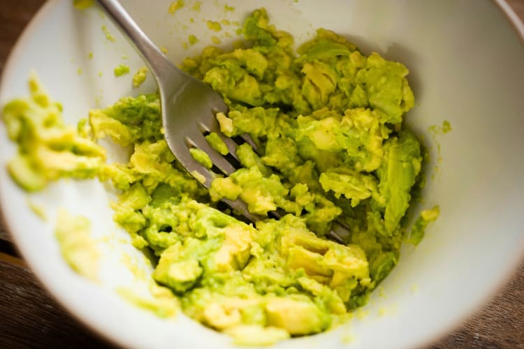 A bowl of mashed avocado with a fork