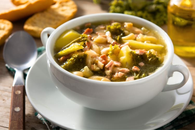 A bowl of cabbage soup next to ingredients 