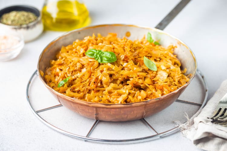 A pan with cooked cabbage next to ingredients