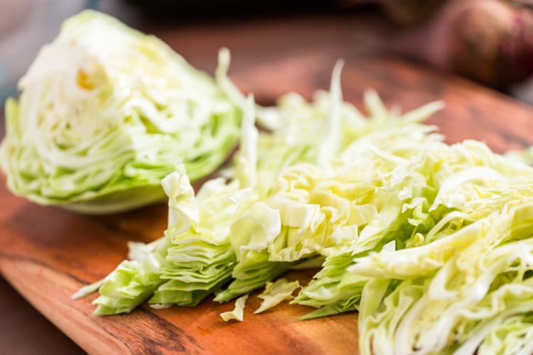 Cabbages next to shredded cabbage on a board